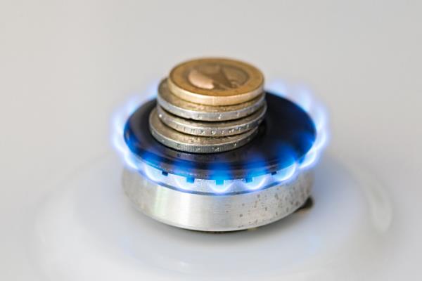 A lit gas burner burns mo<em></em>ney with a blue flame with pound coins on it