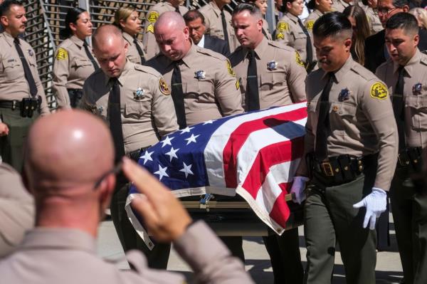 The coffin of Los Angeles sheriff's deputy Ryan Clinkunbroomer is carried out at the Cathedral of Our Lady of the Angels.
