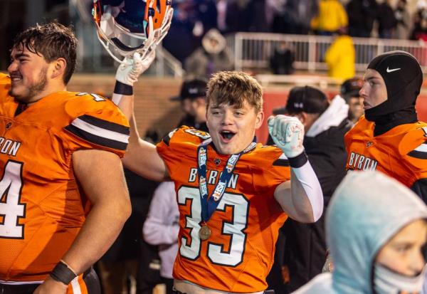Byron’s Carsen Behn, center, celebrates as the team leaves the field after taking a group photo after the championship game on Nov. 24, 2023. 