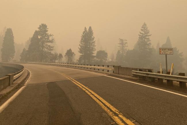 In this photo provided by Caltrans, smoke from the Head Fire blankets the closed State Route 96 in Klamath Natio<em></em>nal Forest, Calif., on Wednesday, Aug. 16, 2023. Rural areas near California's border with Oregon were under evacuation orders Wednesday after gusty winds from a thunderstorm sent a lightning-sparked wildfire racing through natio<em></em>nal forest lands, authorities said. The blaze in Siskiyou County was one of at least 20 fires that erupted as thunderstorms brought lightning and downdrafts that drove the flames through timber and rural lands. (Billy Shakespeare/Caltrans via AP)