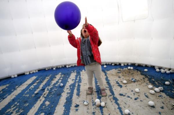 Elinor Silverman plays with a balloon inside an inflatable igloo...