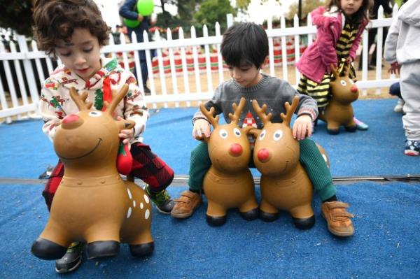 Youngsters ride toy reindeer in the Reindeer Corral during the...