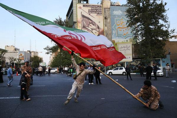 Demo<em></em>nstrators wave a huge Iranian flag backdropped by a building emblazo<em></em>ned with anti-Israeli messages, in Tehran. Picture: AP Photo/Vahid Salemi