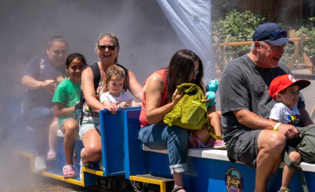 Kids and parents enjoy a mist-filled train ride at the Children’s Museum of So<em></em>noma County during the Great Train Days Saturday, July 22, 2023 in Santa Rosa. (Nicholas Vides / For The Press Democrat)