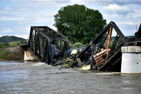 Several train cars are immersed in the Yellowstone River after a bridge collapse near Columbus, Mont., on Saturday, June 24, 2023. The bridge collapsed overnight, causing a train that was traveling over it to plunge into the water below. (AP Photo/Matthew Brown)